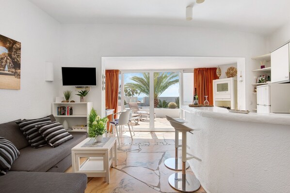 A modern living room with a sofa, TV, and a dining area.