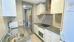 Uma cozinha compacta com uma pia de aço inoxidável, forno embutido e fogão.