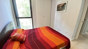 Quarto com cama, janela, guarda-roupa e quadro na parede.