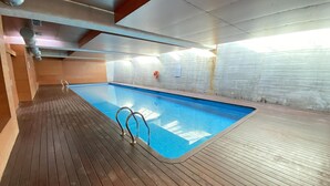 Uma piscina interna com piso de madeira e parede revestida de azulejos.