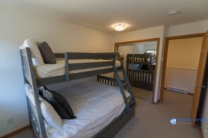 Une chambre avec un lit superposé, un luminaire au plafond, une porte et un miroir sur le mur.
