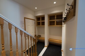 Un couloir avec un escalier en bois, une porte blanche et des étagères intégrées.