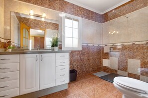 Ein Badezimmer mit großem Spiegel, Waschbecken, Toilette und Duschbereich.
