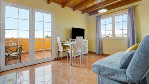 A room with a wooden ceiling, a sofa, a desk with a computer, and a dining area with chairs. - Vacation Home "Casa Paco 3" with Sea View, Private Terrace & Shared Pool (Costa Calma)