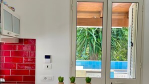 Una cocina con salpicadero rojo, encimera de madera y ventana con vistas al verdor.