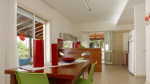 Una cocina moderna con comedor, que incluye una mesa de madera, sillas verdes y un florero rojo.
