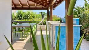 Un espacio al aire libre techado con piscina, lavadora y una mesa con sillas.