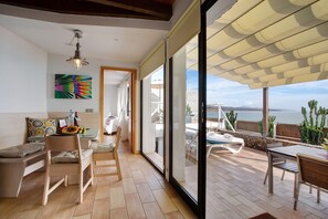 A modern interior with a dining area, a kitchen, and a balcony with a view of the sea.