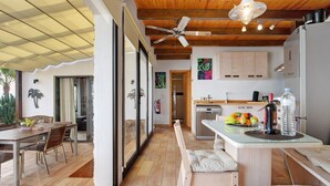 Una cocina moderna con comedor, techo de madera y ventilador de techo.