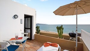 Ein Balkon mit Tisch, Stühlen, einem Grill und Blick aufs Meer.