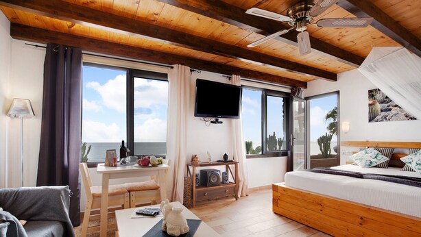 Ein Zimmer mit Bett, Fernseher, Tisch und Meerblick.