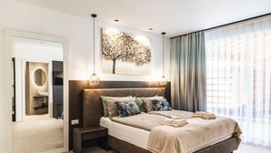Une chambre à coucher moderne avec un grand lit, une table de chevet, un miroir et un tableau représentant un arbre.