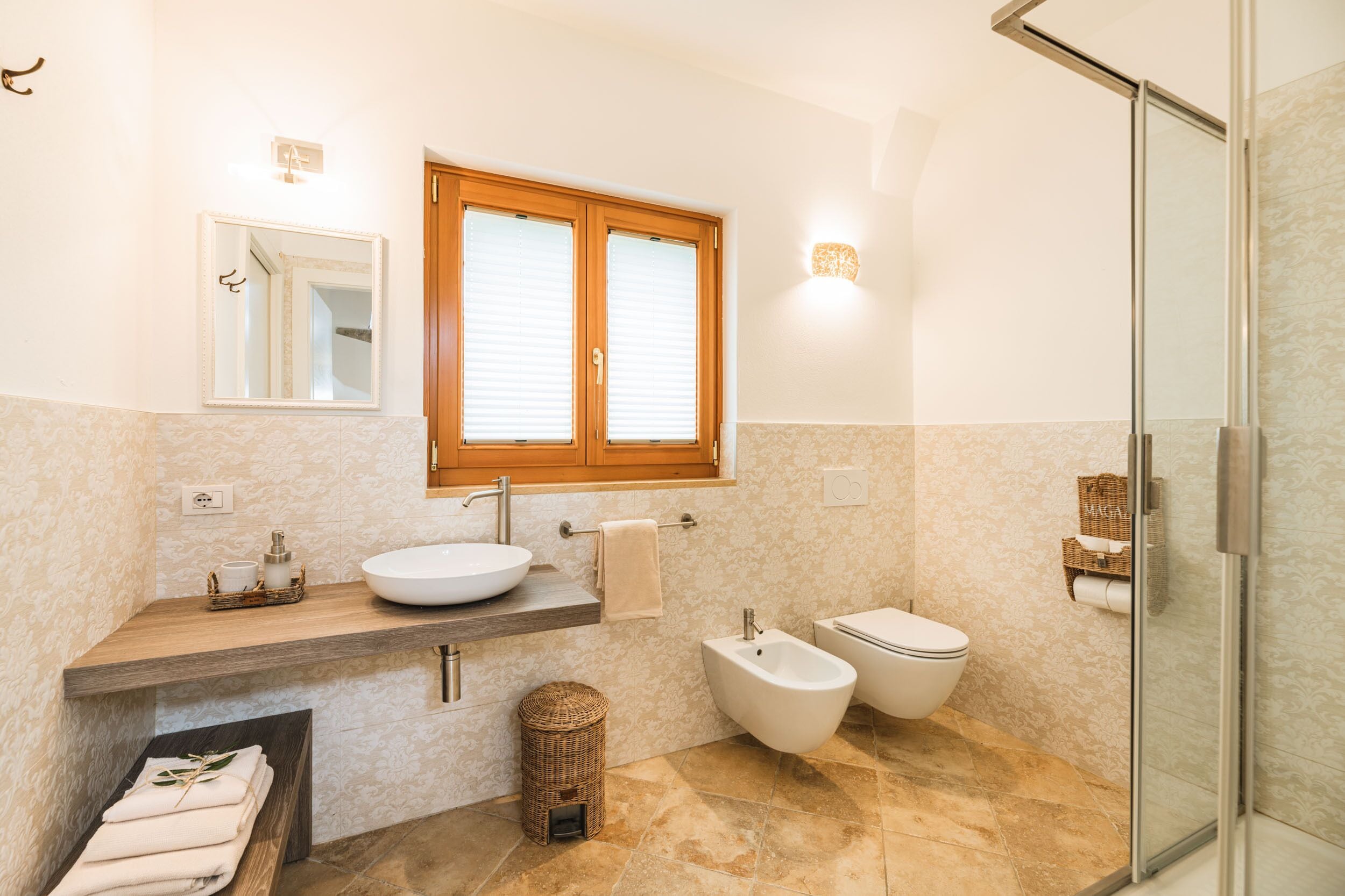 A modern bathroom with a wooden vanity, a freestanding bathtub, and a glass-enclosed shower.