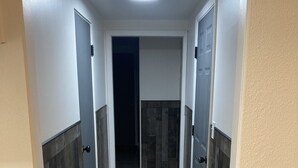 Un pasillo con suelo de madera, paredes blancas y puertas que dan a varias habitaciones.