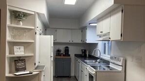 Una cocina moderna con armarios blancos, horno empotrado y un cubo de basura negro.