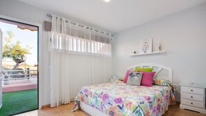 A bedroom with a bed, a nightstand, a window with curtains, and a view of a balcony. - Holiday Apartment "Paulalucía" with Mountain View, Shared Pool & Wi-Fi (Costa de Antigua)