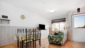 A modern living space with a dining area, a sofa, a television, and a window with a view. - Holiday Apartment "Paulalucía" with Mountain View, Shared Pool & Wi-Fi (Costa de Antigua)