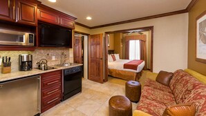 A compact hotel room with a kitchenette, a bed, and a sofa.