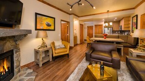 A spacious living room with a fireplace, leather sofas, a dining area, and a kitchen in the background.