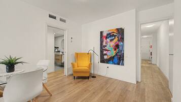 Una sala moderna con comedor, un sillón amarillo y un cuadro abstracto grande en la pared.