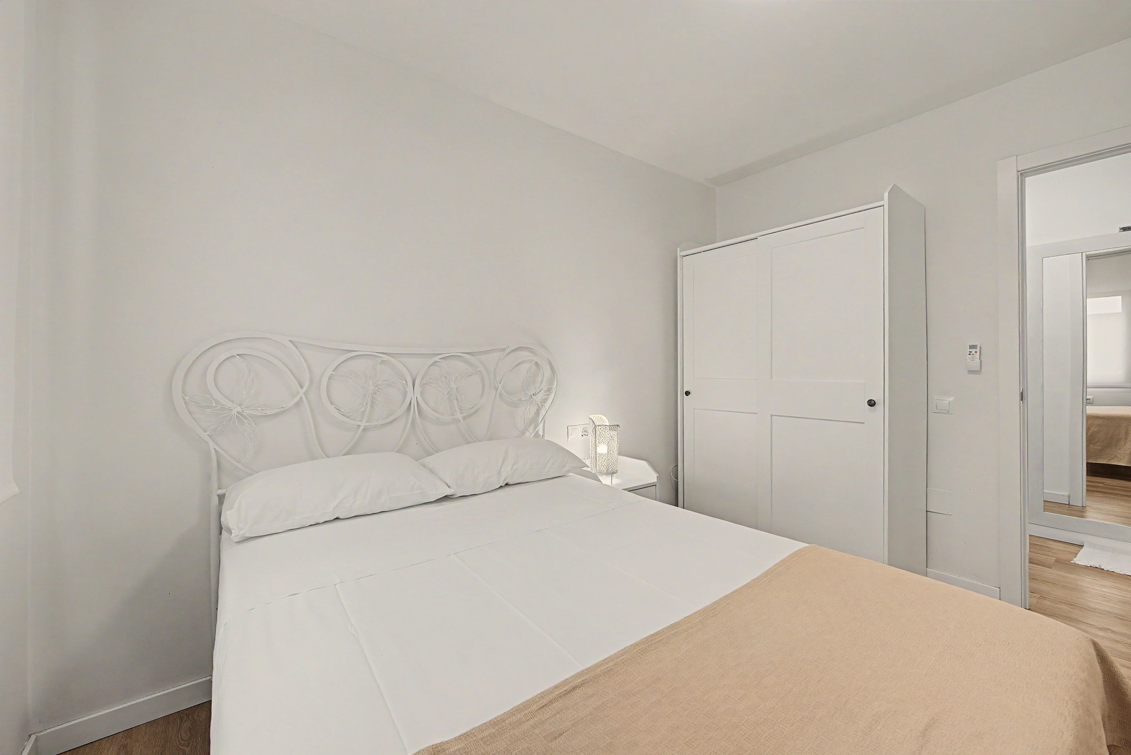 Een slaapkamer met een bed, een kledingkast en een nachtkastje.