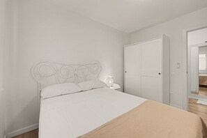 Un dormitorio con cama, armario y mesita de noche.