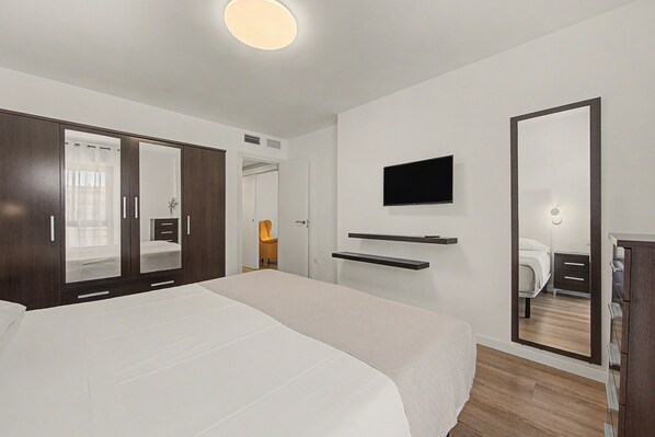 A hotel room with a large bed, a wardrobe, a television, and a mirror.