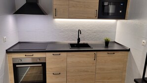 Una cocina moderna con armarios de madera, encimera negra, horno empotrado, microondas y fregadero.