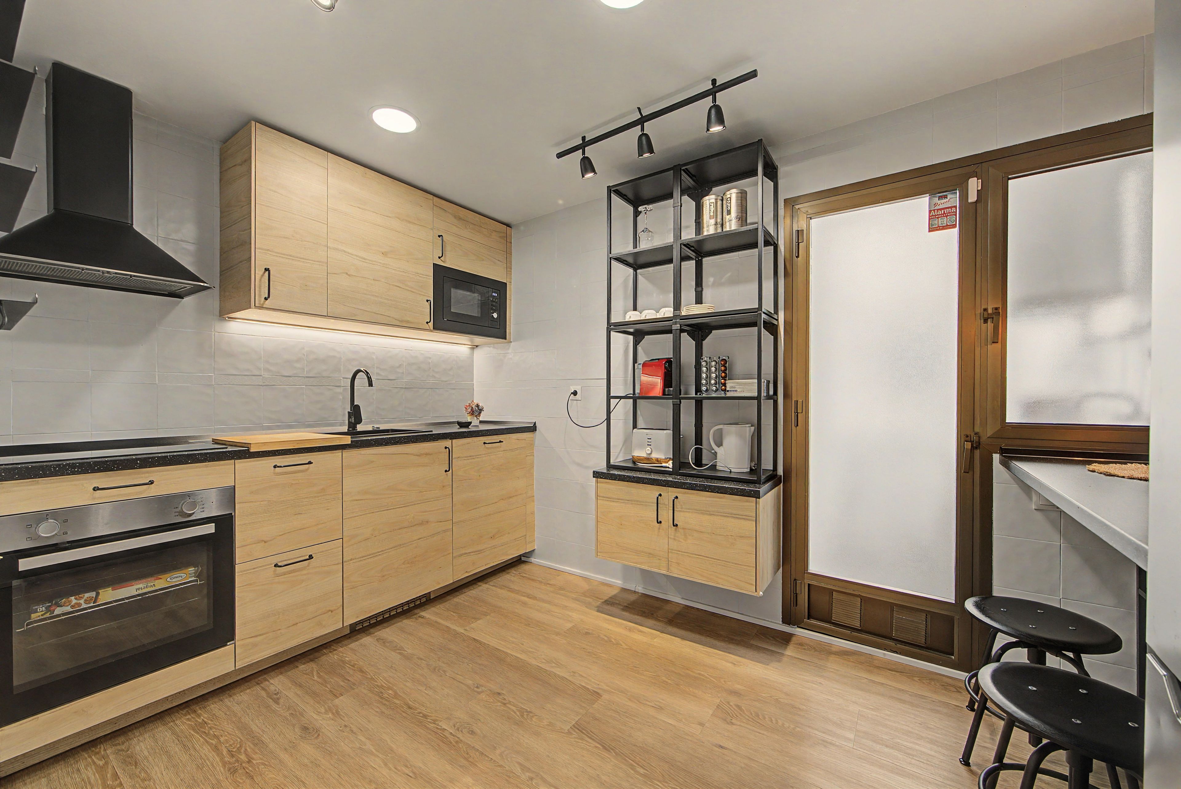 A modern kitchen with wooden cabinets, a built-in microwave, a stainless steel oven, and a black countertop.