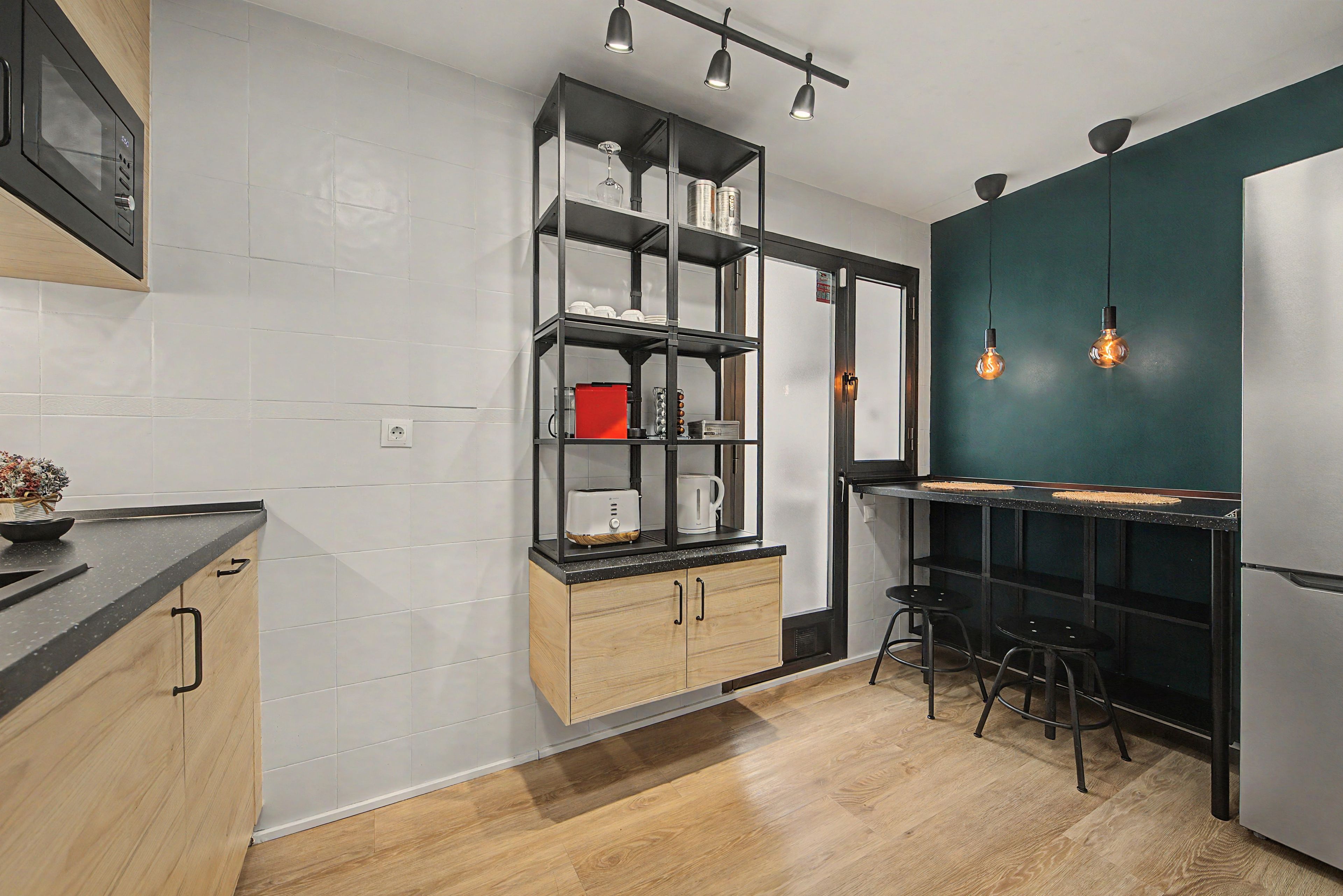 Una cocina moderna con encimera de madera, horno integrado y una estantería colgante negra.