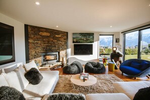 Relax in this cozy living space with a fireplace, comfortable seating, and a large window offering a view of the surrounding mountains.