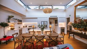 Un comedor amplio con techos altos, cocina moderna y ventanas grandes.