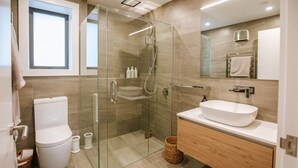 Un baño moderno con ducha acristalada, lavabo blanco y retrete.