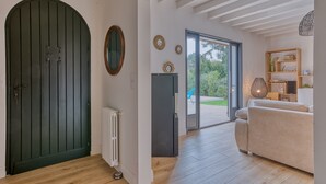 A room with a green door, a white radiator, a sofa, and a wooden shelf with decorative items. - 4-Star Villa Arcachon – Heated Pool, Garden & Petanque, Sleeps 8 (La Teste-de-Buch)