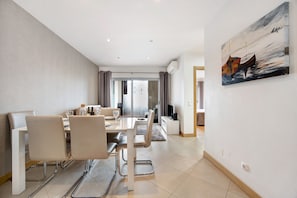 A modern dining area with a table set for two, a sofa, and a television in the background.