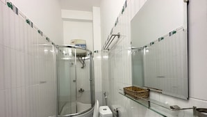 Une salle de bain dotée d’une douche à parois de verre, de toilettes et d’un lavabo avec une étagère en verre.