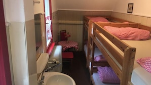 A small, compact room with bunk beds, a sink, and a table with a red and white checkered tablecloth. - Bergwaldhütte  (Bühl)