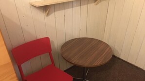 A small room with a round wooden table and a red chair. - Bergwaldhütte  (Bühl)