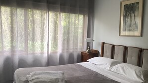 En snyggt bäddad säng med vita sängkläder, ett sängbord med en lampa och en tavla på väggen.