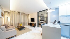 A modern living room with a sofa, coffee table, and TV. There is a kitchen area with a counter and cabinets. - GLOUCESTER HOTEL CHEONGJU (Cheongju)