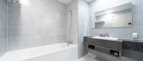 Un baño moderno con una bañera, ducha, tocador con espejo y un perchero para toallas.
