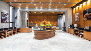 A modern reception area with a central island, wooden paneling, and a marble floor. - GLOUCESTER HOTEL CHEONGJU (Cheongju)