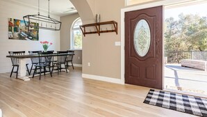 A spacious dining area with a wooden table and chairs, a chandelier, and a large window. - Spacious-Gourmet Kitchen-Luxe King Bed-Ping Pong-Arcade (Sonora)