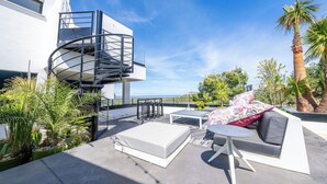 Une terrasse sur le toit avec un escalier en colimaçon, du mobilier d’extérieur et une vue sur l’océan.