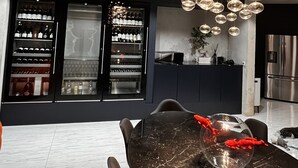 Une cuisine moderne dotée d’un plan de travail en marbre, d’un luminaire sphérique suspendu et d’un réfrigérateur à vin.
