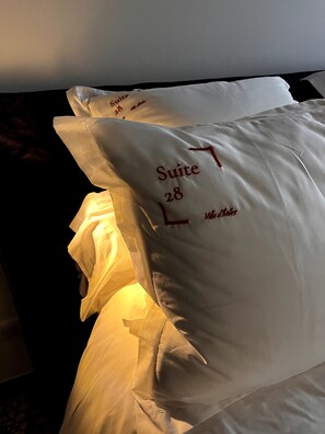 Ein Hotelzimmer mit einem Bett, ausgestattet mit Kissen, die "Suite 28" und "Villa Notes" zeigen.