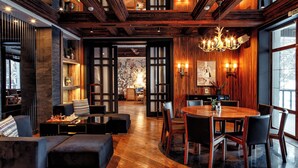 A modern interior with a wooden ceiling, a dining area with a round table and chairs, and a cozy seating area with a fireplace. - Dom u ozera  (Burabay)