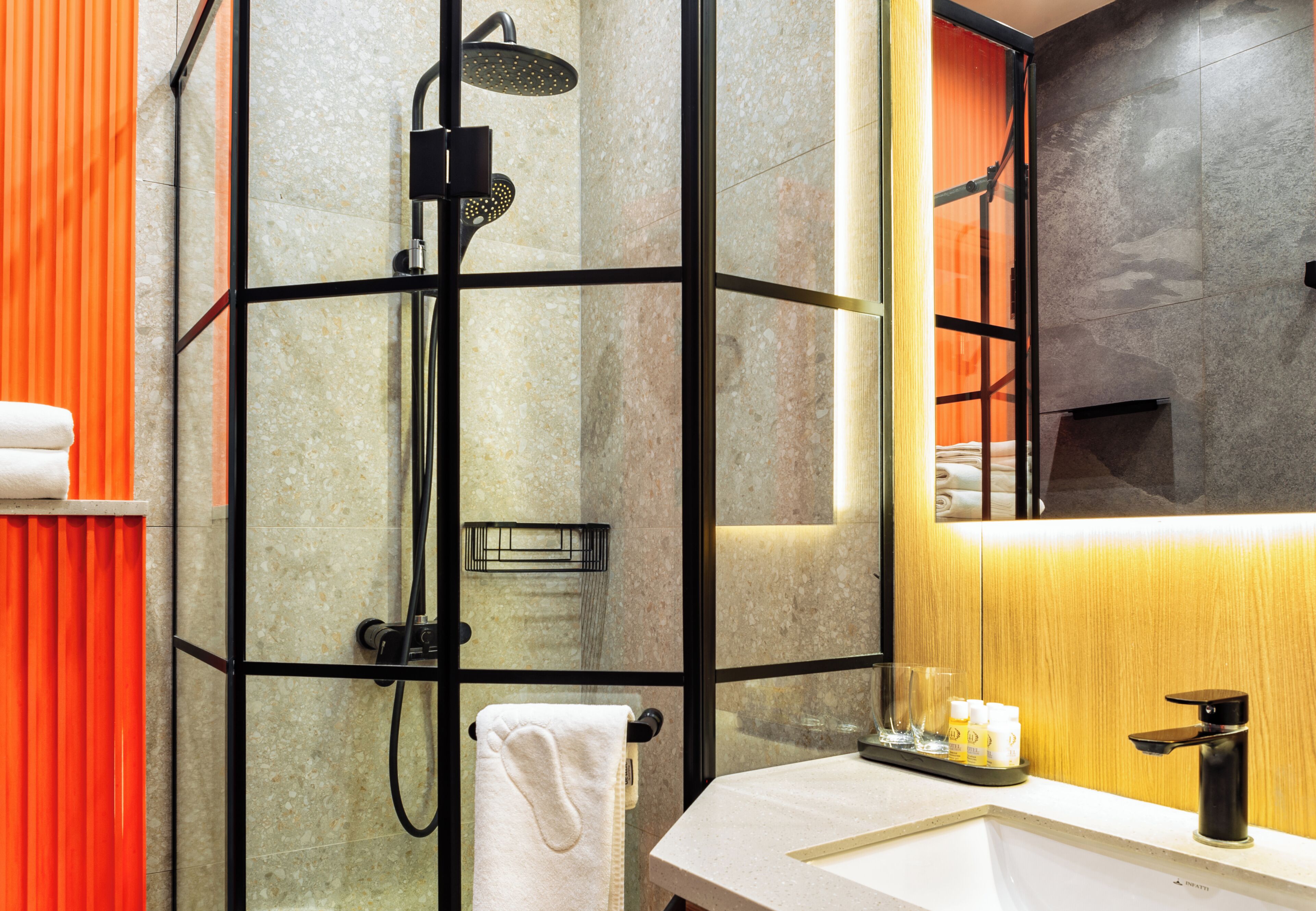 A modern bathroom with a glass-enclosed shower, a wooden vanity, and a large mirror.