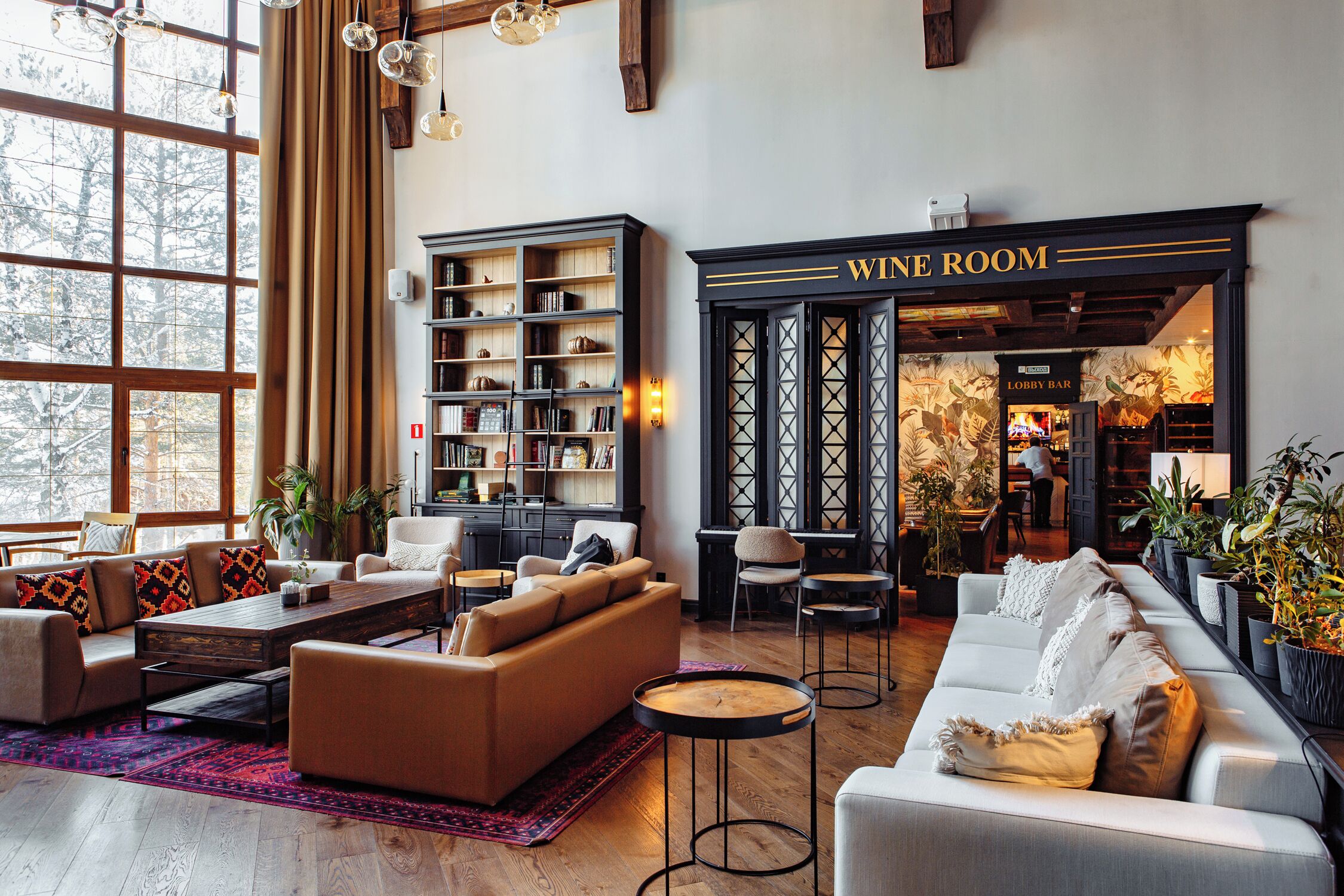 A cozy lounge area with sofas, a coffee table, and a bookshelf. There's a 'WINE ROOM' sign and a 'LOBBY BAR' visible.
