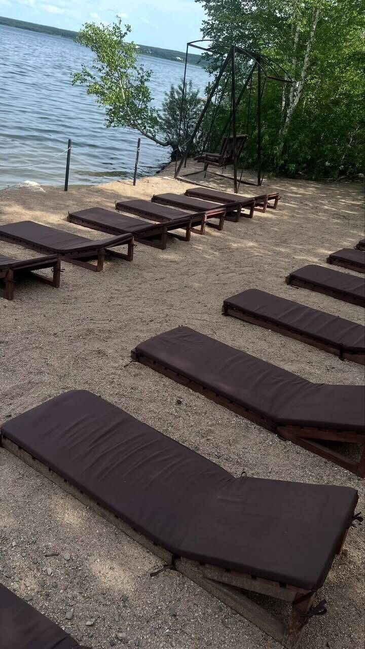 A beach with sun loungers and a swing set.